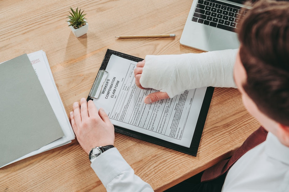 A worker with broken arm filling workers' compensation form